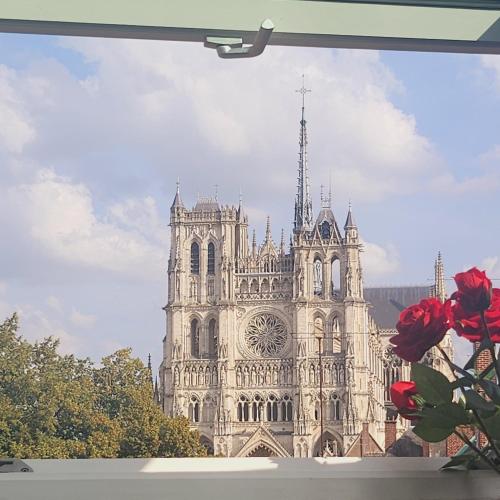 une grande cathédrale avec des roses rouges devant elle dans l'établissement Splendid Cathedral à 50m Amiens centre FreeParking, à Amiens