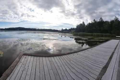 a dock on a body of water with a cloudy sky at Väsjöbacken, Sollentuna, Stockholm in Sollentuna
