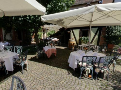 eine Gruppe von Tischen und Stühlen mit weißen Sonnenschirmen in der Unterkunft Hotel-Restaurant Drei Hasen in Michelstadt