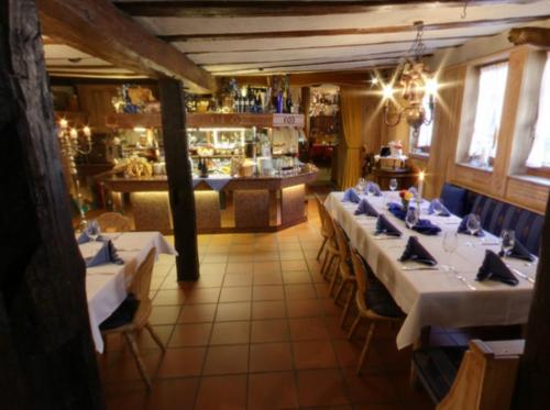 uma sala de jantar com mesas e cadeiras brancas e um restaurante em Hotel-Restaurant Drei Hasen em Michelstadt