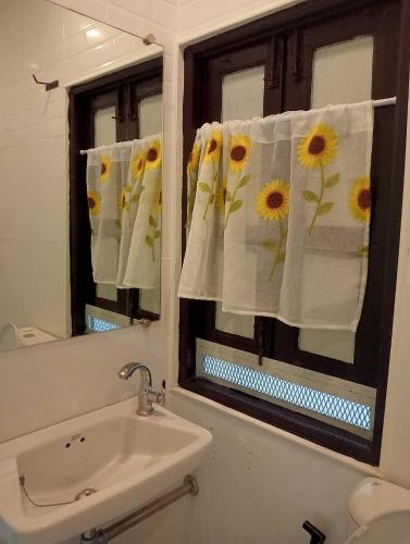 a bathroom with a sink and a mirror with sunflower towels at เขายัอยวาเล่ย์ in Khao Yoi