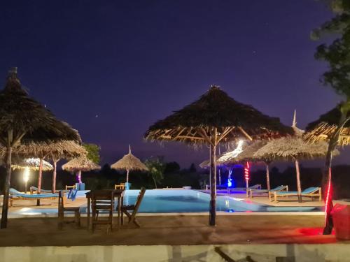 - Piscina con sillas y sombrillas por la noche en Five Seasons Zanzibar opposite Mnemba island Hotel, en Makunge