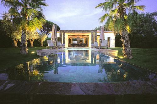 a swimming pool in front of a house with palm trees at Magnifique villa à louer piscine salle de sport in Grimaud