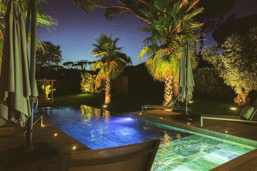 une piscine avec parasols et palmiers la nuit dans l'établissement Magnifique villa à louer piscine salle de sport, à Grimaud