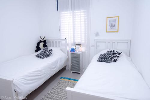 a bedroom with two beds and a panda bear pillow at יפעת הגלבוע -סוויטות אירוח ברמה אחרת in Nurit