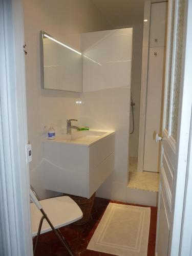 une salle de bain blanche avec un lavabo et un miroir dans l'établissement Au coeur de Paris, à Paris