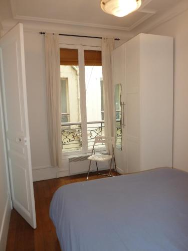 une chambre blanche avec un lit et une fenêtre dans l'établissement Au coeur de Paris, à Paris