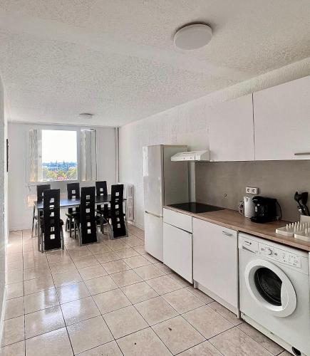 une cuisine avec des armoires blanches et une table et des chaises dans l'établissement Appartement T5 Spacieux, à Lyon