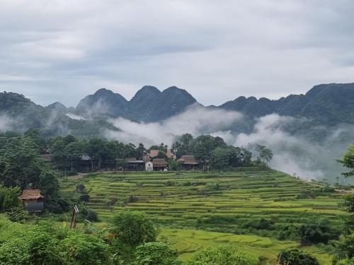 a village in a field with mountains in the background at Inh La Home Pu Luong in Pu Luong