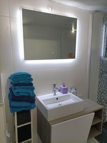 une salle de bain avec un lavabo, un miroir et des serviettes dans l'établissement Penty atypique ,calme et à deux pas du centre, à Châteaulin