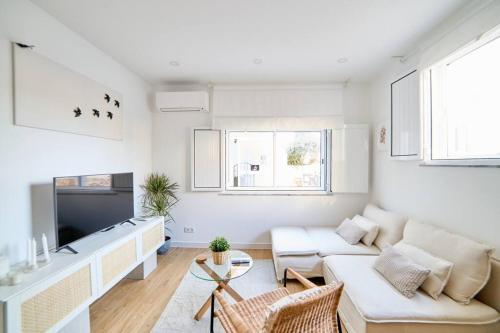 a white living room with a couch and a tv at La Perla Blanca in Lagos