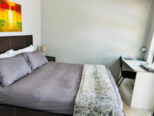 a bedroom with a bed with a desk and a painting at SapzRes at Klerksdorp in Klerksdorp