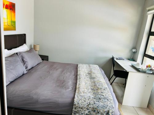 a small bedroom with a bed and a desk at SapzRes at Klerksdorp in Klerksdorp