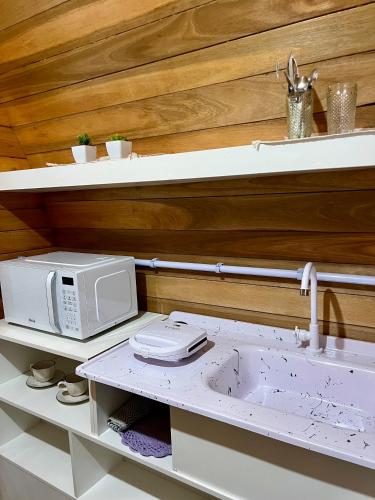 a microwave sitting on top of a kitchen shelf at Chalé Barril com cozinha in São Francisco do Sul