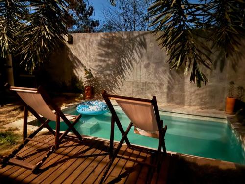 two chairs sitting on a deck next to a swimming pool at Casa Monika in Puerto Escondido