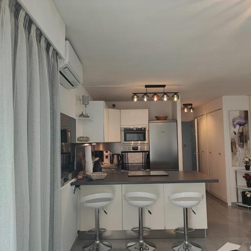une cuisine avec des armoires blanches et des tabourets de bar dans l'établissement Cap d'Agde centre port, au Cap d'Agde