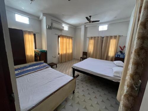 a bedroom with two beds and a ceiling fan at IK Homestay in Varanasi