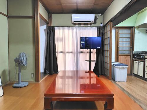 a living room with a table and a tv in it at Old style japanese house Minpaku Yanoya in Otsu
