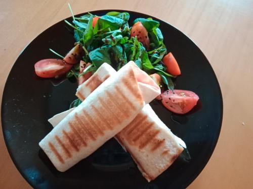 a black plate of food with sandwiches and a salad at Penzion Václav in Hnojní