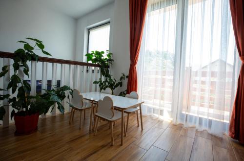 a dining room with a table and chairs and large windows at Dor de Maramu' in Ieud