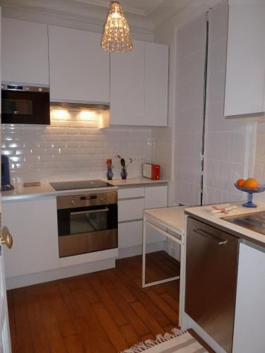 une cuisine avec des armoires blanches et un meuble lumineux dans l'établissement Au coeur de Paris, à Paris