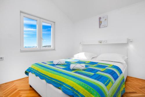 a white bedroom with a bed with a colorful blanket at Apartment Damir in Brodarica