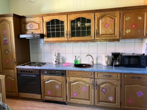 a kitchen with wooden cabinets and a sink and a stove at Doppelzimmer vom Friesenhof Wieratal in Nobitz