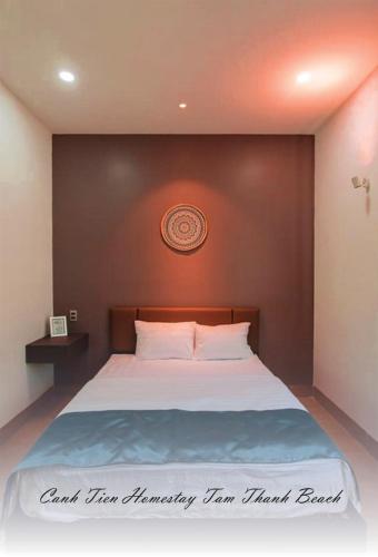 a bedroom with a large white bed with a clock on the wall at Canh Tien Homestay Tam Thanh Beach in Tam Kỳ