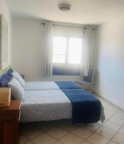 a bedroom with a bed and a window and a chair at Apartamento Vista Famara 2 in Famara