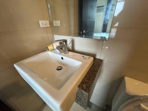 Un baño con lavabo, espejo e inodoro. en Gentry Manor Balcony fast WIFI Okada complex near Airport&MOA 12B, en Manila
