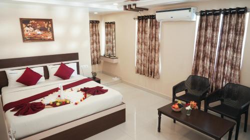 a bedroom with a bed and a chair and a table at Hotel Mountview Comforts in Tirupati