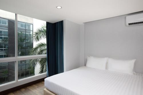 a bedroom with a bed and a large window at Nantra Sukhumvit 39 in Bangkok