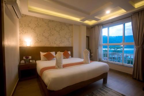 a bedroom with a bed and a large window at Hotel Lake Himalaya in Pokhara