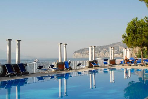 a swimming pool with chairs and the ocean in the background at Grand Hotel Europa Palace in Sorrento