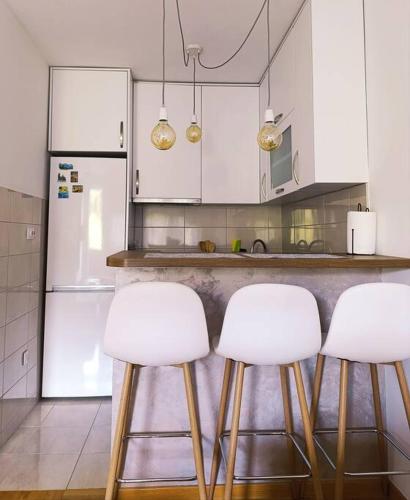 a kitchen with white cabinets and white stools at Stan na dan - apartman Istočno Sarajevo - Lukavica in Vranješ