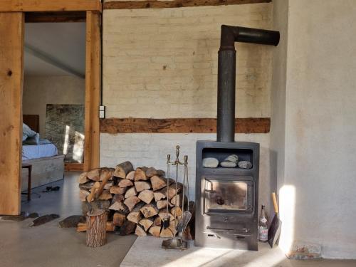 a wood stove in a room with a pile of logs at Huset i Oreby in Sakskøbing
