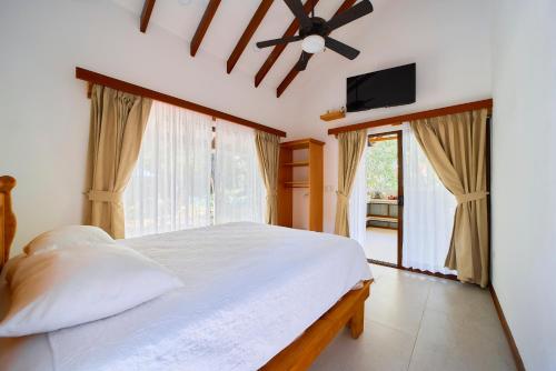 a bedroom with a bed and a ceiling fan at Casa Coki - Modern Villa Pool Steps From the Beach in Puerto Viejo