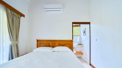 a bedroom with a white bed and a mirror at Casa Coki - Modern Villa Pool Steps From the Beach in Puerto Viejo