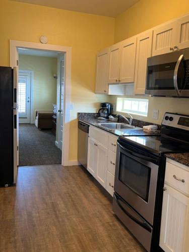 a kitchen with white cabinets and a black appliances at Seashell Village Resort near the beach with kitchens in Port Aransas