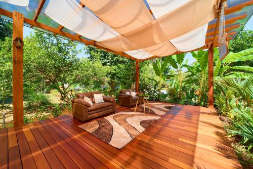 a wooden deck with two chairs and a large umbrella at Casa Coki - Modern Villa Pool Steps From the Beach in Puerto Viejo