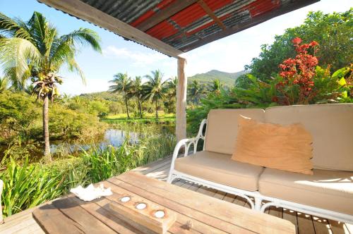 a porch with a couch and a view of a river at Le Cabanon in Choisy