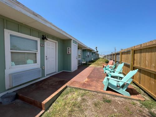 a row of houses with blue chairs on a sidewalk at Seashell Village Resort near the beach with kitchens in Port Aransas