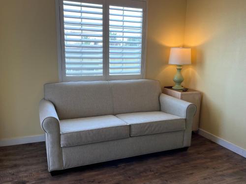 a couch in a room with a window and a lamp at Seashell Village Resort near the beach with kitchens in Port Aransas