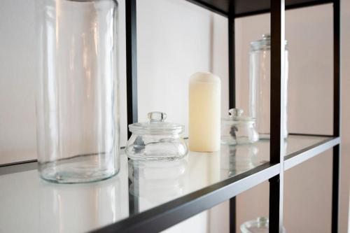 Un estante con jarrones de cristal y una vela encima. en Maisonette Wohnung Bolkerstraße in Düsseldorf, en Düsseldorf