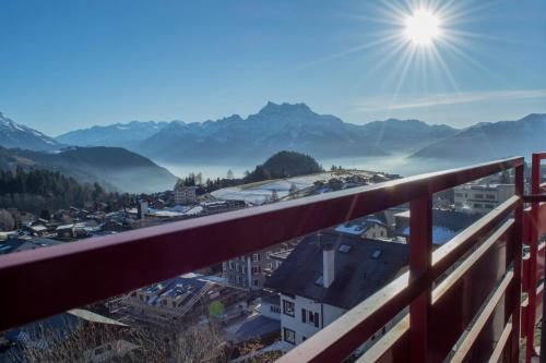 a view of a city from a balcony with the sun in the sky at Alpine Classic Hotel in Leysin
