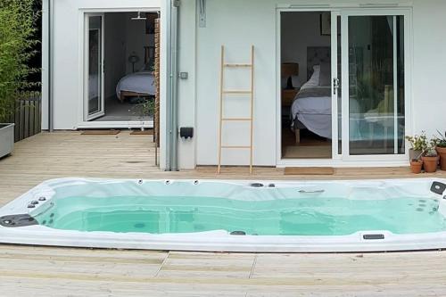 a hot tub on a patio with a house at Relaxing private entrance ensuite room with stunning sea view and swimspa in Saint Lawrence