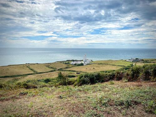 a lighthouse on top of a grassy hill with the ocean at Relaxing private entrance ensuite room with stunning sea view and swimspa in Saint Lawrence