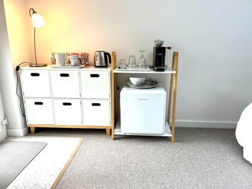 a room with two white cabinets and a coffee maker at Relaxing private entrance ensuite room with stunning sea view and swimspa in Saint Lawrence