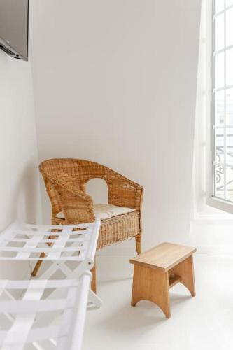 une chaise en osier et un tabouret dans une chambre avec fenêtre dans l'établissement Charming Studio Ideally Located in Paris, 9th, à Paris