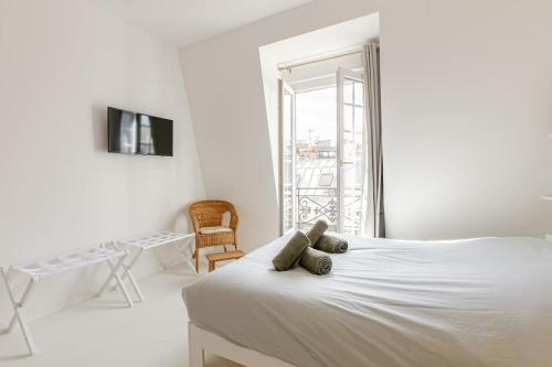 une chambre blanche avec un lit et un balcon dans l'établissement Charming Studio Ideally Located in Paris, 9th, à Paris